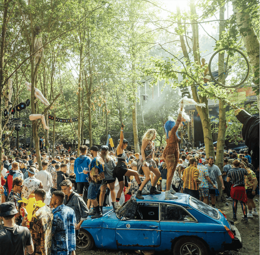 Festivalgoers dancing among the trees at Lost Village